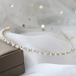 Dettaglio del cerchietto dorato con perle bianche su tulle glitterato morbido
