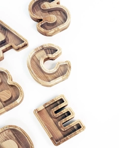 Close-up of wooden alphabet shaped money boxes with clear acrylic covers and natural grain