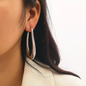 Close-up of oversized silver teardrop hoop earring in polished finish on model