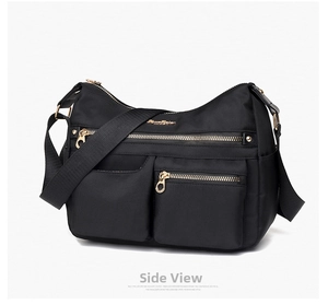Detailed view of black nylon crossbody bag with golden zippers and multiple pockets
