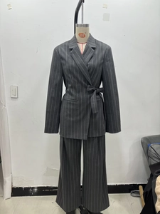 Vue avant d'un ensemble de costume gris à rayures avec blazer ceinturé et pantalon large