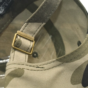 Détail de la boucle en métal vintage et du tissu en toile camouflage sur la casquette de baseball