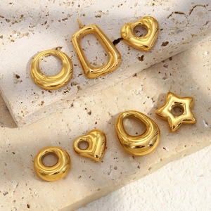 Close-up of geometric 18K gold-plated stainless steel hollow charms on marble