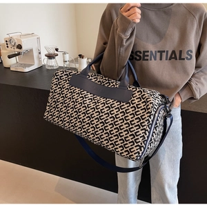 Dettaglio di una grande borsa da viaggio in tela con motivi geometrici e manici in pelle