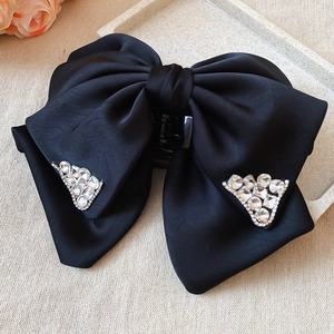 Detail of elegant black satin bow hair claw clip with sparkling rhinestone accents