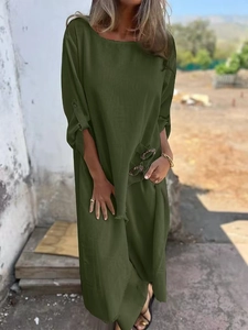 Detail of army green loose fit long robe set with metallic buttons in a rustic outdoor setting