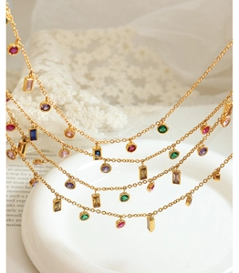 Close-up of a layered gold necklace with colorful round and rectangular gemstones