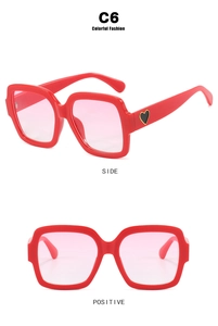 Detailansicht der roten quadratischen Sonnenbrille mit pinken Verlaufsgläsern und Herz-Dekor