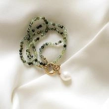 Detail of green beaded bracelet with baroque pearl and gold toggle clasp on silk