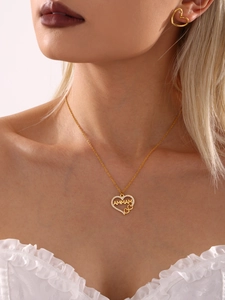 Gros plan d'un ensemble collier et boucles d'oreilles cœur MAMMA doré sur mannequin