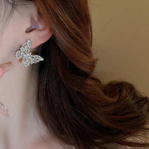 Detail view of butterfly drop earrings with sparkling rhinestones worn on a model ear