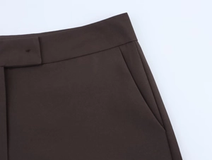 Detailed close-up of dark coffee waistline with buttonhole and side slant pockets