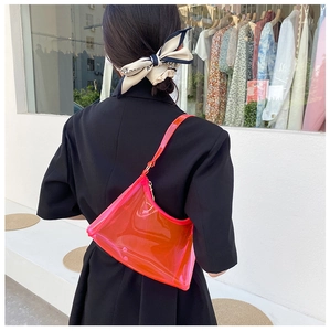 Close-up of stylish neon orange transparent PVC baguette bag worn by model