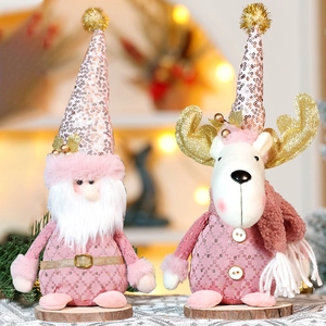Pink and gold Christmas gnome and reindeer plush ornaments on rustic wooden bases