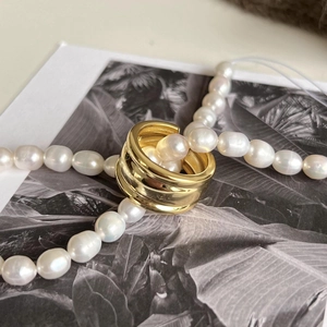 Macro shot of minimalist gold multilayer ring with pearls on vintage botanical card