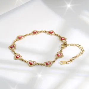 Detail of gold heart link bracelet with red evil eye charms and star flare effect