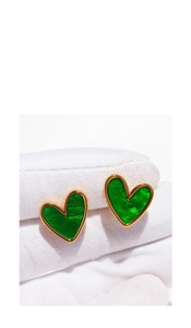 Detailed macro view of green heart stud earrings with vintage gold textured metal edges