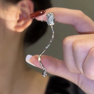 Macro shot of silver rose ear cuff with sparkling zircon and wavy tassels detail