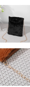 Detail of black plush crossbody bag featuring metal chain strap and warm textured background