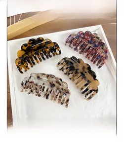 Close-up of four large acetate hair claws in various patterns like marble and tortoise shell