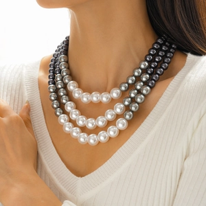 Detail of three-layer faux pearl necklace featuring white and grey beads on a model