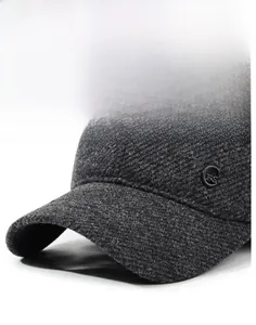 Detailed view of dark grey wool blend fabric and round metal logo on a men's winter cap