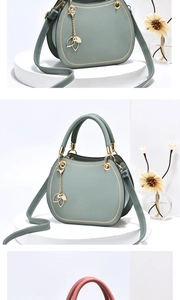 Detail of grey-blue semi-circular leather handbag with elegant gold leaf pendant