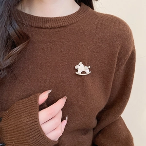 Detail of horse brooch with cream enamel and zircons on brown knitted sweater