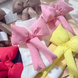 Women cotton slouch socks with detachable 3D bows in multiple colors on a wooden tray