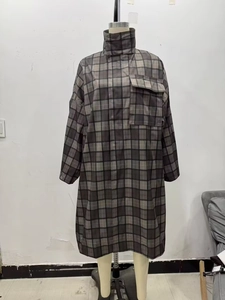 Detail of oversized plaid trench coat featuring a high collar and a large chest pocket