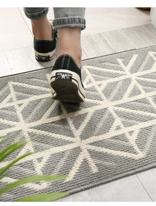 Macro view of grey and white geometric woven doormat showing dust-resistant texture