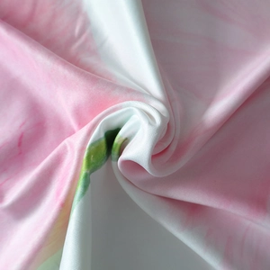 Detailed macro view of pink floral fabric texture with green prints and soft satin finish