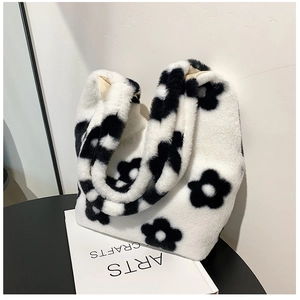 Close-up of plush floral shoulder bag with black and white flower patterns on a table