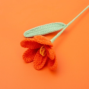 Close-up of handmade crochet orange tulip with green leaves and high texture detail