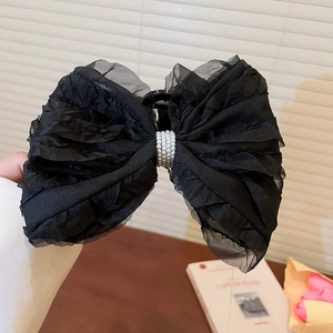 Détail d'une grande pince à cheveux avec nœud en résille noir et perle