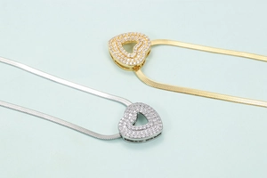 Macro detail of gold and silver heart pendants with micro-pave stones on herringbone chain