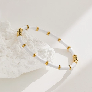 Chic bamboo style white enamel bangle with gold accents on white stone background