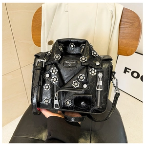 Detail of black jacket-shaped crossbody bag featuring metal zippers and rhinestone flowers