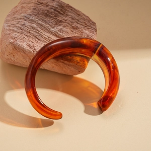 Macro detail of amber resin cuff bracelet showing natural textures on a rock
