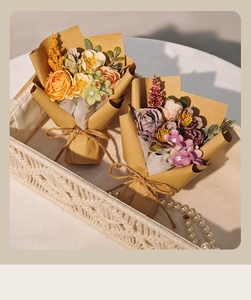 Artistic close-up of mini silk rose bouquets in a woven tray with pearl necklace decor