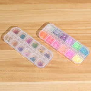 Détail des boîtes de 12 compartiments avec paillettes papillons et fleurs séchées colorées