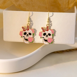 Detail of skull earrings with rose and butterfly elements on golden hooks