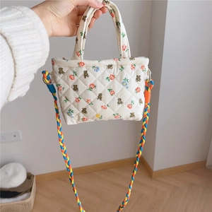 Close-up of quilted floral bear pouch featuring a thick colorful braided shoulder strap