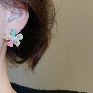 Close-up of elegant flower stud earrings with mint green and pink enamel and pearl center