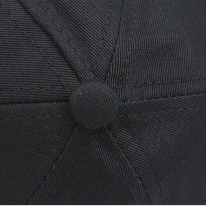 Macro detail of the black cotton twill cap top with reinforced stitching and button
