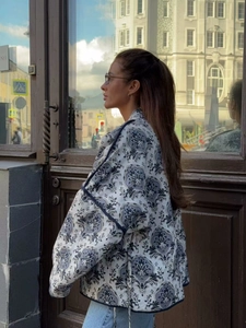 Detailed close-up of a white quilted jacket with a navy paisley print and dark piped edges