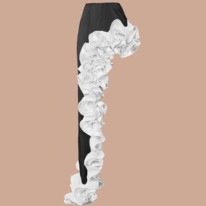 Detail of oversized white layered ruffles on the side of black high-waisted trousers