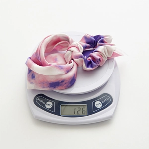Pink and purple tie-dye fabric scrunchie with streamers being weighed on a scale