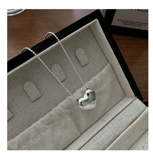 Close-up of a silver heart pendant necklace on a jewelry box with elegant bead chain