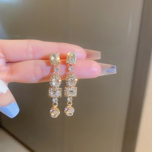Detailed close-up of golden geometric earrings with sparkling zircon crystals
